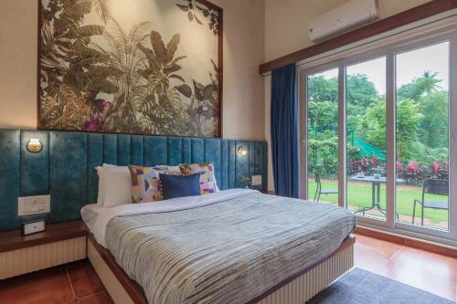 um quarto com uma cama grande e uma janela grande em Prism and Palette by StayVista - Nestled amidst greenery, offering vibrant interiors, a swimming pool, snooker table, gazebo, and a spacious lawn area em Alibaug
