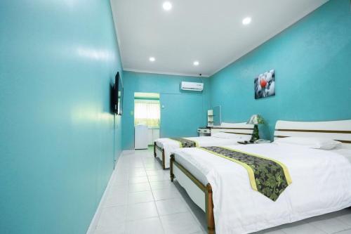 two beds in a room with blue walls at Beach Garden Hotel in Saipan