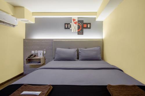 a bedroom with a large bed with blue pillows at Infiniti Hotel in Jakarta