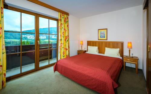 Schlafzimmer mit einem roten Bett und einem großen Fenster in der Unterkunft Hotel-Pension Schwaighofen in Eugendorf
