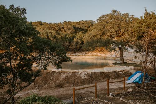 a body of water with trees and a fence at Hummingbird Haus - Hill country views on 20 acres with firepit in Spring Branch