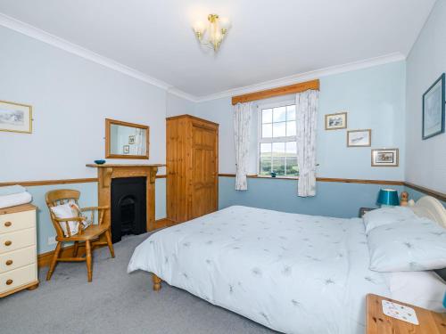 a bedroom with a bed and a chair and a fireplace at Brokan Fourwinds in Okehampton