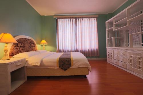 a bedroom with a bed with a dresser and a window at Beach Garden Hotel in Saipan