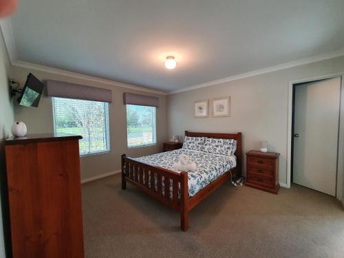 a bedroom with a bed and a dresser and two windows at Hideaway By the Bay in Busselton