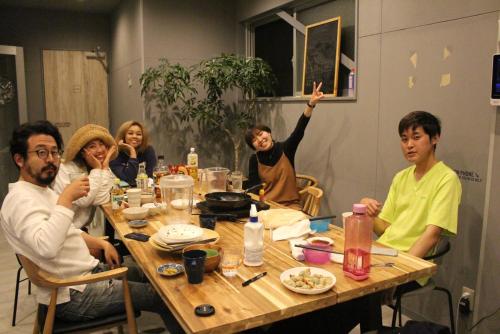 a group of people sitting around a table at Hostel STAND BY ME in Fukuoka