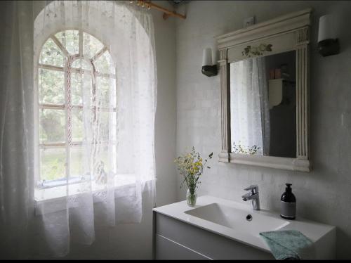 uma casa de banho com um lavatório e uma janela em Landlig idyl på Dommergården Bed and Coffee em Læsø