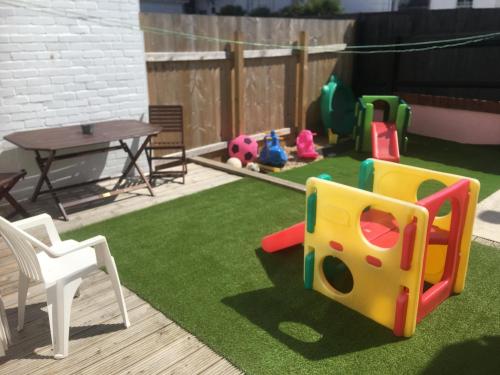 a backyard with a playground with a table and chairs at PAIGNTON S ONLY Ground floor Garden 2 Bedroom Apartment in front of the Pier & your Very own Private FREE Car space ,2 Double beds , 2 Single Beds , Kitchen , Air Fryer , 50 Blue ray Films ,Hotel Reception to Greet & Happily Help you in Paignton