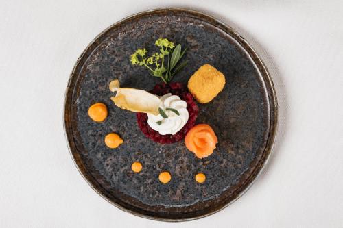 a black plate with food on a white table at Naturhotel Landhof Irschen in Irschen