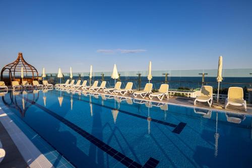 uma grande piscina com cadeiras brancas e água em MARITIM Hotel Amelia - Luxury Ultra All Inclusive em Albena