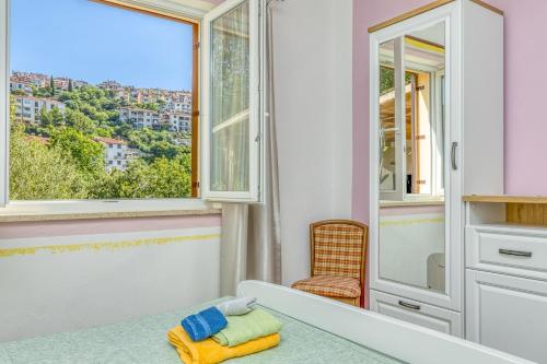 um quarto com uma janela, uma cama e uma cadeira em Apartments Vivijana em Rabac