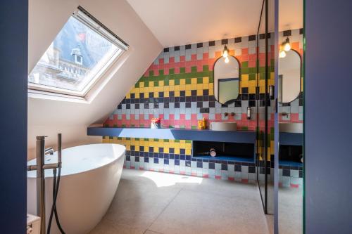 a bathroom with a tub and a colorful tile wall at P6 Antwerp in Antwerp