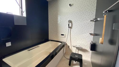 a bathroom with a tub and a shower and a stool at Yokosuka Sky Grey -横須賀- in Yokosuka