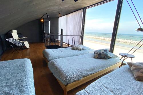 een slaapkamer met 2 bedden en uitzicht op het strand bij Yokosuka Sky Grey -横須賀- in Yokosuka