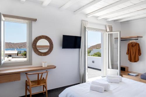 a bedroom with a bed and a desk and a window at Nautilus Serifos in Livadakia