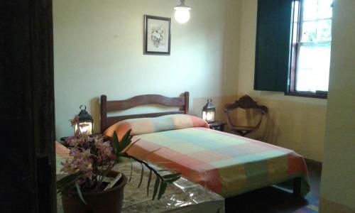 a bedroom with a bed and a table with flowers at Pouso Realeza in Tiradentes