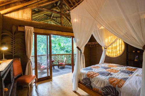 a bedroom with a canopy bed and a balcony at Bamboo Turtles Ecolodge in Ubud