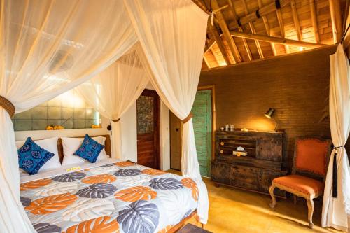 a bedroom with a bed with curtains and a chair at Bamboo Turtles Ecolodge in Ubud