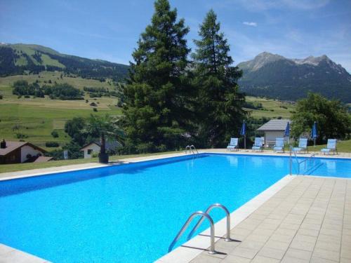 a large blue swimming pool with mountains in the background at Tgesa Sunnmatt 24 in Savognin