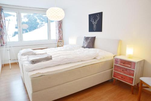 a bedroom with a large white bed with a window at Tgesa Sunnmatt 24 in Savognin