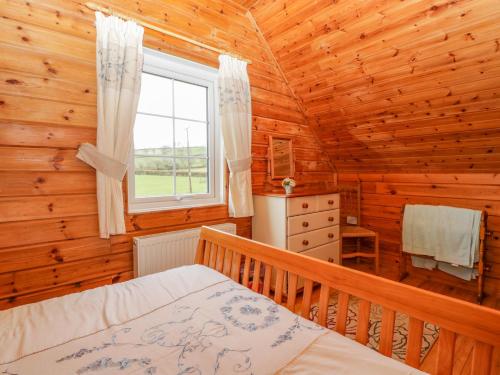 ein Schlafzimmer mit einem Bett und einem Fenster in einem Blockhaus in der Unterkunft Orchard Lodge in Wellington