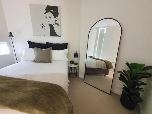 - une chambre avec un lit et un miroir dans l'établissement Harbour Escape Apartments Docklands, à Melbourne