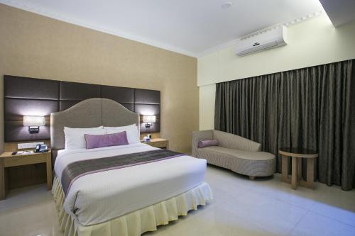 a hotel room with a large bed and a chair at Ascott Palace Dhaka in Dhaka