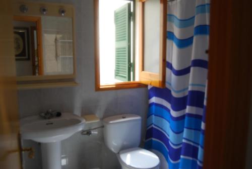 a bathroom with a sink and a toilet and a mirror at Es Pins in Cala Blanca