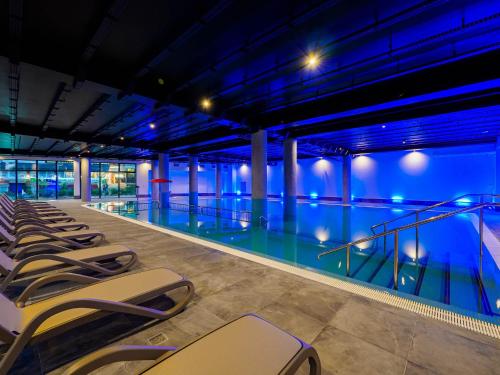 a swimming pool with a row of chairs next to it at Resort Król Plaza Spa & Wellness in Jarosławiec