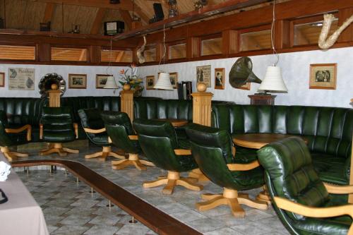 a dining room with green leather chairs and a table at Aparjods in Sigulda