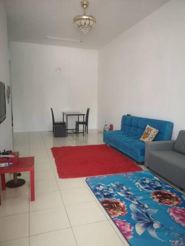 sala de estar con sofá azul y alfombra roja en Homestay near to Uum, Changlun., en Changlun