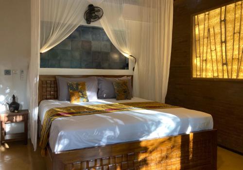a bedroom with a large bed with white sheets and a window at Bamboo Turtles Ecolodge in Ubud