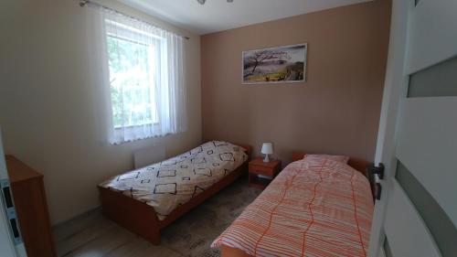 a bedroom with two beds and a window at Domek Ewy in Święta Katarzyna