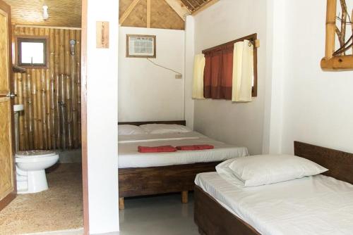 a bedroom with two beds and a bathroom with a toilet at OcamOcam Azur Inn in Busuanga
