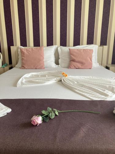 a white bed with a flower on the floor at Lira Beach Studio in Mamaia
