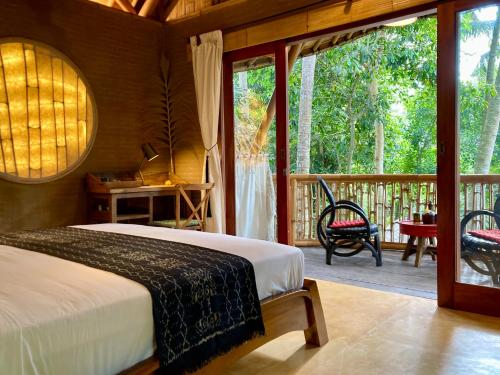 a bedroom with a bed and a balcony at Bamboo Turtles Ecolodge in Ubud