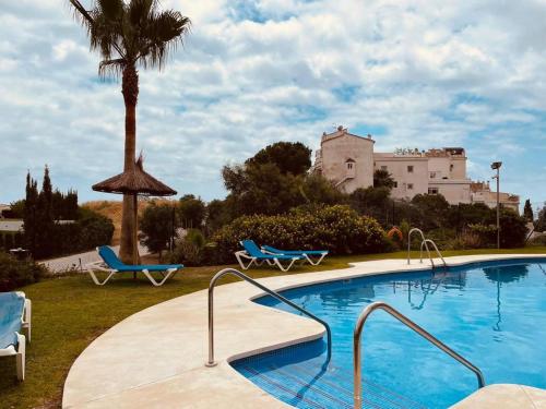 a swimming pool with two blue chairs and a building at Appartement Paraiso Riviera del Sol-Mijas in Málaga