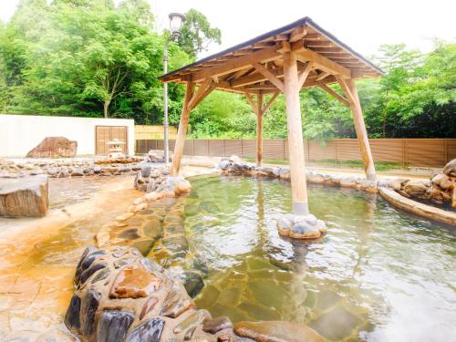 a pond with a wooden gazebo in a zoo at SPA HOTEL YUTTARIKAN in Satsumasendai