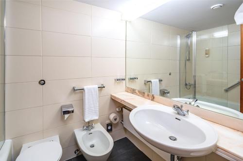 La salle de bains est pourvue d'un lavabo, de toilettes et d'un miroir. dans l'établissement AHORN Harz Hotel Braunlage, à Braunlage