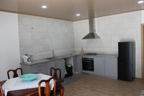 a kitchen with a table and a black refrigerator at Casa do Avô Pedro in Lagar Novo