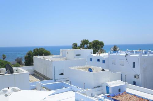 a group of white buildings with the ocean in the background at Dar Hammamet Guest House & Hammam in Hammamet