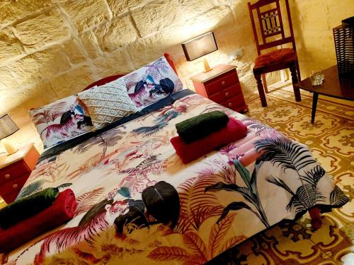 una cama con un edredón colorido y almohadas en ella en The LYNDEE HOUSE en Nadur