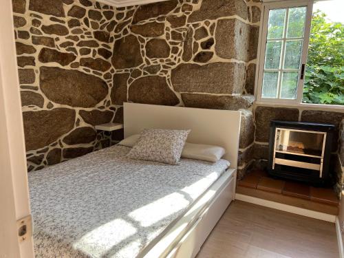 a bedroom with a stone wall with a bed and a fireplace at Villa Parra in Santa Cristina de Cobres