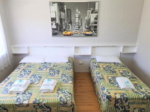 2 Betten in einem Zimmer mit einem Bild an der Wand in der Unterkunft Maria Motel in Moree