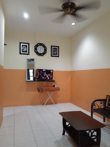 um quarto com uma ventoinha de tecto e um relógio na parede em Homestay Idaman 2 em Bukit Kayu Hitam