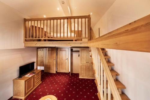 an attic room with a staircase and a television at Hotel Tannbergerhof im Zentrum von Lech in Lech am Arlberg