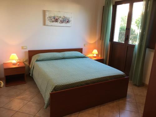 ein Schlafzimmer mit einem Bett, zwei Lampen und einem Fenster in der Unterkunft Borgo Saraceno Mirto 5 in San Pasquale