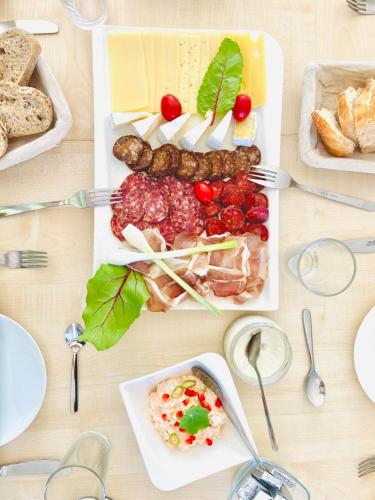 a table topped with plates of food with meat and vegetables at A16 Design Panzió in Harkány