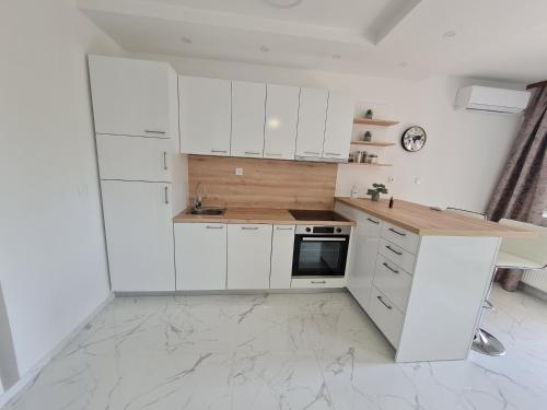 a white kitchen with white cabinets and a counter at Apartmani MODUS - self service check-in in Virovitica