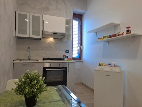 a kitchen with white cabinets and a table with a plant at Civico85 in Naples