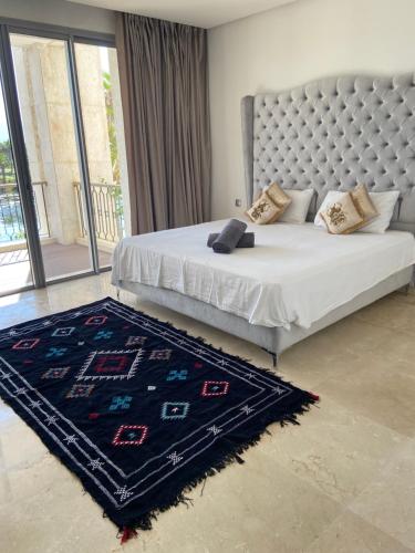 a bedroom with a large bed with a blue rug at Luxueux appartement Ritz Carlton Marina Smir in Sania Torres